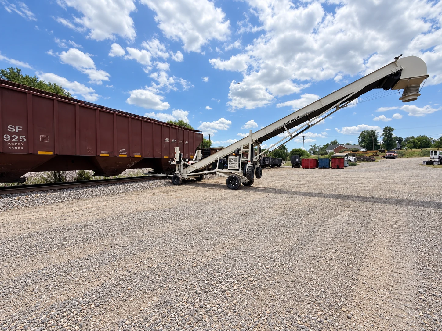 Hopper-bottom railcar beside a mobile unloading conveyor