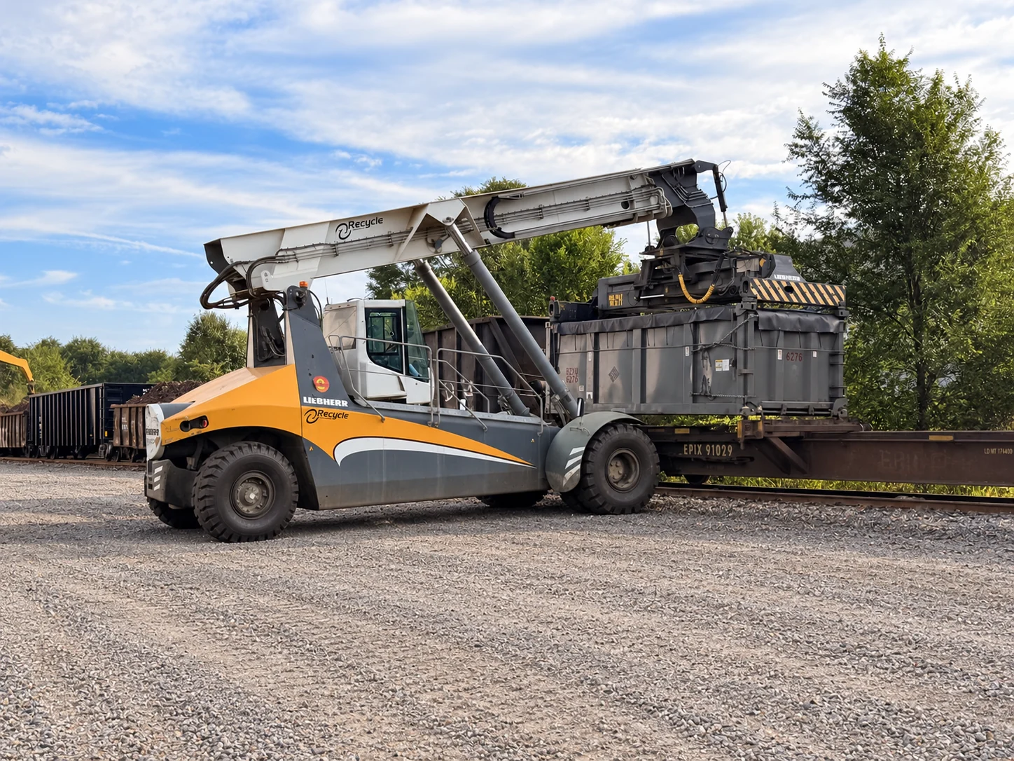 Liebherr reach stacker handling an intermodal container beside a railcar