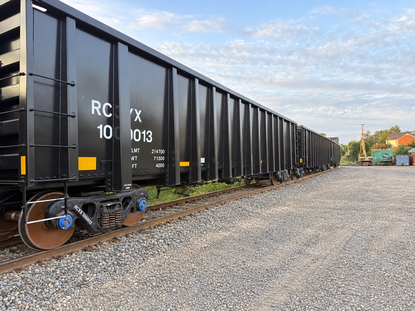 Black RCYX high-sided railcars on a rail siding